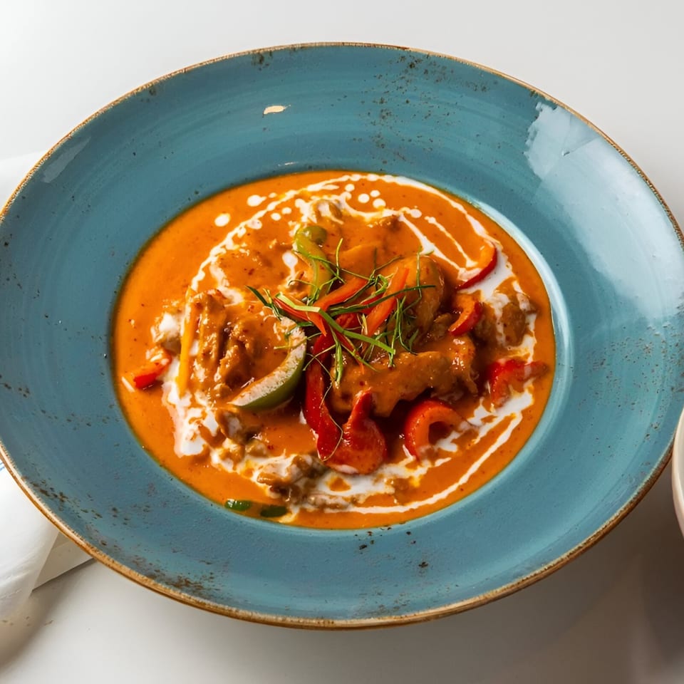 Osha Thai Kitchen's red curry with chicken, bell peppers, and lime in a blue bowl.