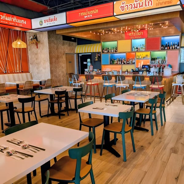 Osha Thai Kitchen's vibrant dining room with colorful bar, wooden floors, and set tables.